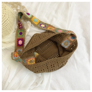 Detail of bohemian knit tote bag with colorful crochet floral strap and brown openwork weave