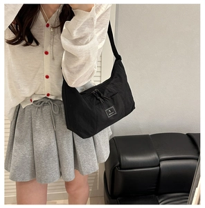 Close-up of black nylon tote bag featuring drawstring pockets and letter F logo detail