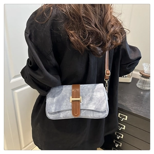 Détail du sac baguette bleu clair avec bandoulière en cuir marron et boucle dorée