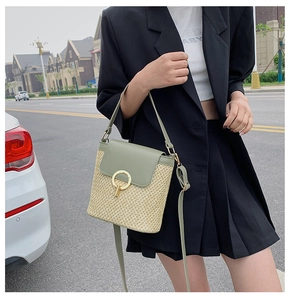 Close-up of woven straw handbag with light green leather flap and gold ring buckle