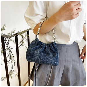 Detail of blue denim bucket bag featuring sparkling finish and silver bead handle strap