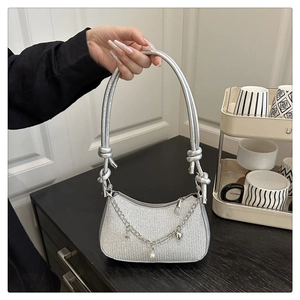 Detail of silver glitter half-moon bag with decorative metal chain and charms
