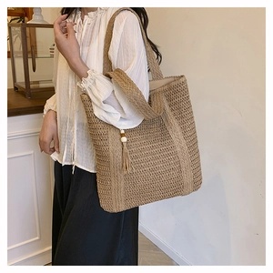 Detail of hand-woven straw tote bag with side fringe and wooden beads on shoulder strap