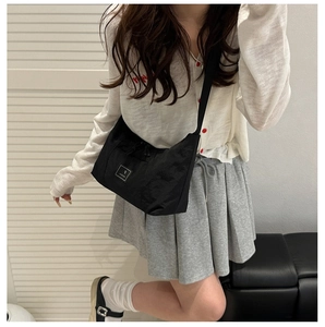 Detail of black nylon crossbody bag with square label and adjustable fabric strap