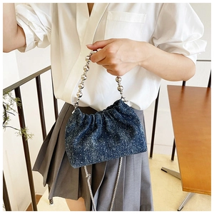 Close-up of denim drawstring bucket bag with silver star-like rhinestones and chain strap