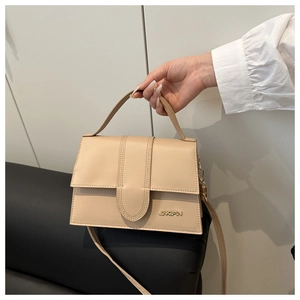Détail du sac à main en cuir beige minimaliste avec logo doré et poignée élégante