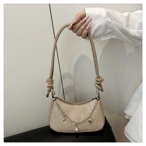 Detailed shot of champagne sequined shoulder bag with silver charms and pearl pendant