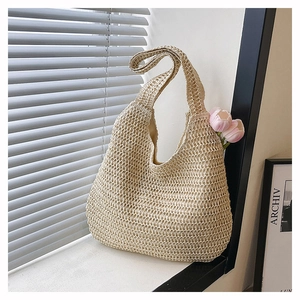 Detail of hollow-out beige woven straw shoulder bag with a wide strap and fabric lining
