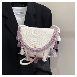 Dettaglio borsa intrecciata bianca con ricamo etnico e nappe viola decorative