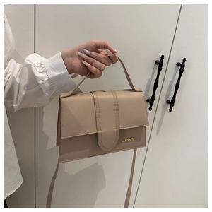 Détail du sac en cuir beige avec boucle magnétique, poignée et bandoulière réglable