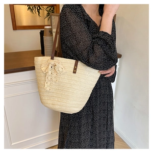 Close-up of beige woven tote bag featuring a lace bow and brown faux leather straps