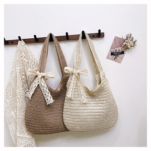 Detail of hand-woven straw shoulder bags with lace bows in brown and beige colors