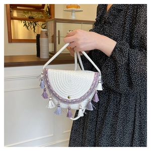 Dettaglio della borsa a tracolla intrecciata boho con nappe viola e ricami etnici