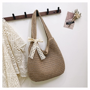 Detail showing natural straw woven tote bag with delicate cream lace bow decoration