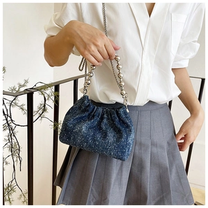 Detail of blue denim polka dot bucket bag featuring silver beaded handle and chain strap