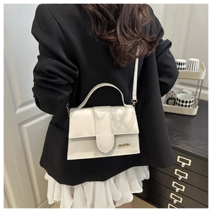 Sac carré crème chic avec logo doré porté par un mannequin pour l'effet de taille