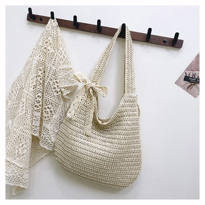 Detail of beige hand-woven hobo bag featuring a decorative side bow and cotton rope texture