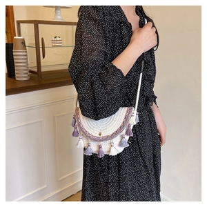 Dettaglio della borsa a tracolla boho intrecciata con nappe viola e ricami etnici
