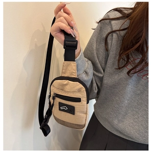 Dettaglio della borsa a tracolla in nylon kaki con tasca frontale con zip e patch logo