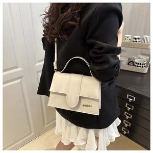 Détail du sac bandoulière blanc cassé avec logo doré et bandoulière réglable élégante