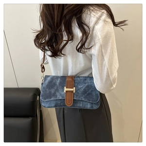 Vue détaillée du sac baguette en denim bleu avec sangle en cuir brun et boucle dorée
