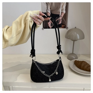 Detail of black sequined handbag featuring silver chain with heart and star charms