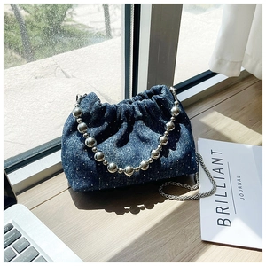Close-up of blue denim bucket bag with sparkling rhinestones and silver beaded handle