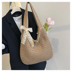 Detail of hand-woven straw tote with a white lace bow accent on a natural fiber texture