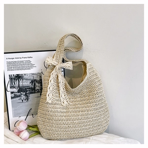 Detail of hand-woven straw tote bag with elegant lace bow decoration and honeycomb texture