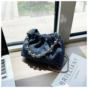 Close-up of denim bucket bag with sparkling studs, silver bead handle, and chain strap