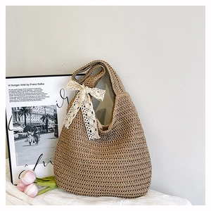 Detail of hand-woven beach bag with large white lace bow and wide shoulder strap