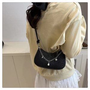 Model wearing black crescent shoulder bag with sparkly fabric and pearl chain charms