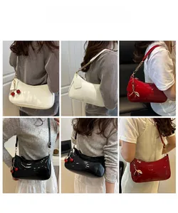 Detail view of glossy patent leather shoulder bags with cherry charms and chain straps