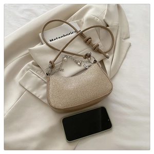Detail of beige crescent shoulder bag with woven texture and pearl star chain strap