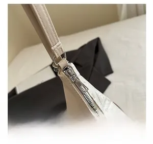 Detail showing the smooth silver metal zipper and beige PU leather stitching on tote bag