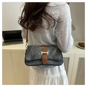 Détail d'un sac baguette gris anthracite avec bandoulière marron sur mannequin