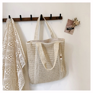 Close-up of the woven straw tote bag featuring intricate textures and a tassel with wood beads
