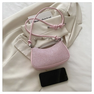 Pink glitter underarm bag with silver chain and pearl details on a cream jacket