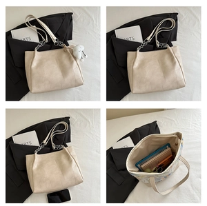 Detail of off-white tote bag showing chain strap, pebble texture, and spacious interior
