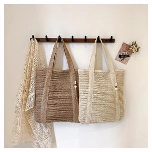 Detail of woven straw tote bags with wooden bead tassels in brown and cream colors