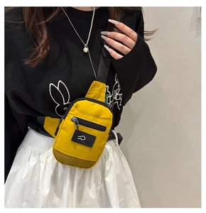 Dettaglio della borsa a tracolla in nylon giallo con tasca a rete e patch logo quadrato