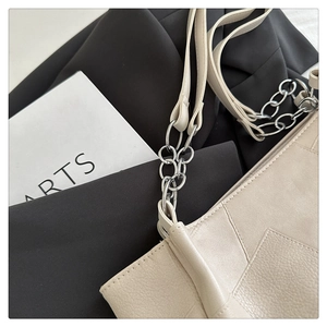 Detailed macro view of beige lychee texture leather and silver metal chain strap
