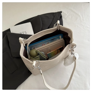 Top view of a beige quilted tote bag showing large capacity with tablet and books