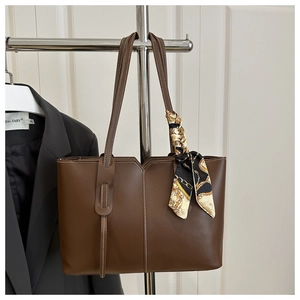 Detail of dark brown leather tote bag with white stitching and decorative silk scarf