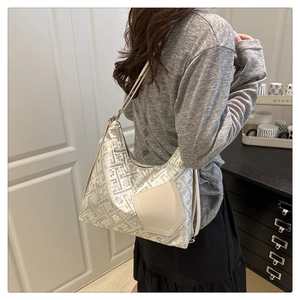 Silver geometric embossed tote bag featuring a beige pocket shown on model's shoulder