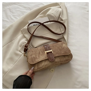 Gros plan détaillé d'un sac baguette en daim marron avec boucle en métal doré et cuir