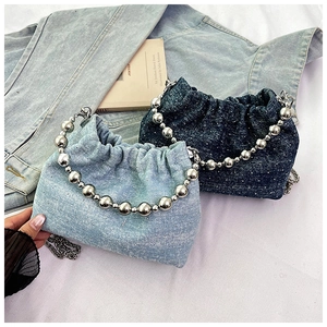 Detail of denim bucket bag with large metal bead handle and silver chain strap