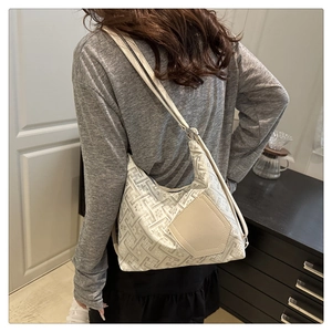 Detail of cream jacquard tote bag with geometric patterns and leather strap on model