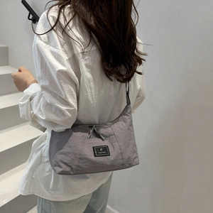 Chic grey crescent shoulder bag in textured nylon fabric with adjustable crossbody strap