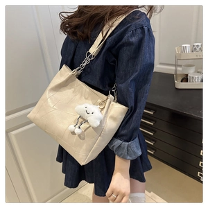 Chic beige tote bag featuring geometric embossing, wide chain strap, and cute cloud charm